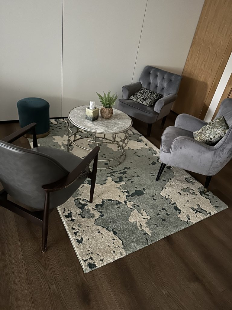A green room with grey armchairs and a stylish rug in white and grey and silver. 